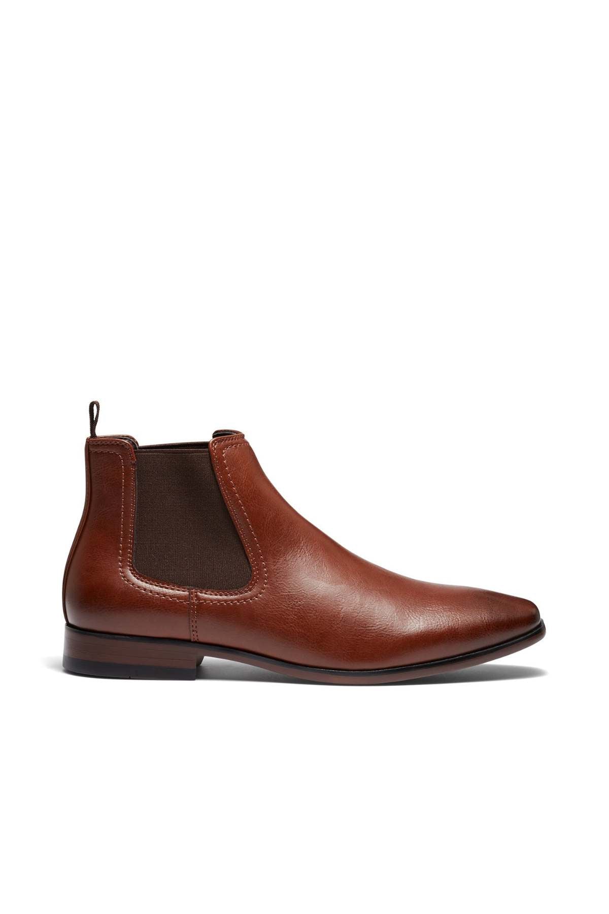 The UNcut Newlands Boot is a brown leather Chelsea boot with elastic side panels and a pull tab at the back. It features an almond toe shape, offering a sleek design with a low heel and smooth finish, making it the perfect versatile boot for any occasion, displayed against a white background.