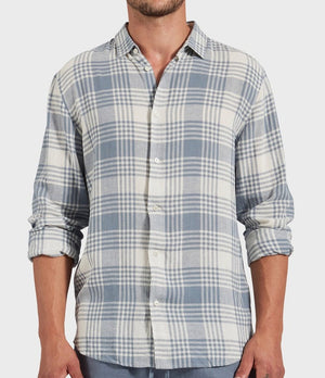 Wearing the Academy Brand Yosemite Shirt, a light blue and white plaid button-up with rolled sleeves made from a linen-viscose blend. Only the torso is visible against a light background, showcasing its relaxed style.