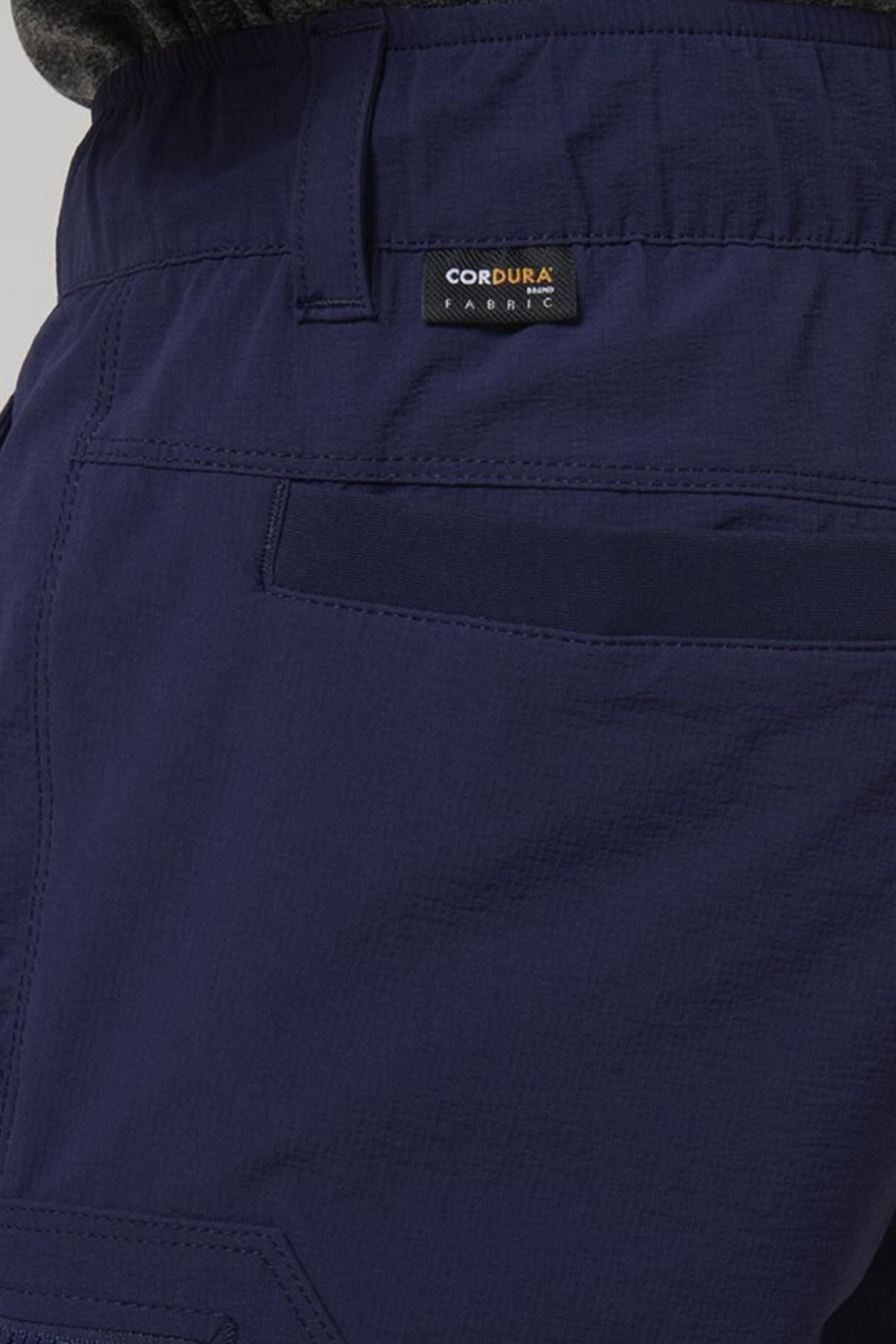 Close-up of the Hard Yakka X Range Mid Short in dark blue stretch Cordura, featuring a back pocket with utility pockets and a small black "CORDURA FABRIC" tag sewn above the pocket.