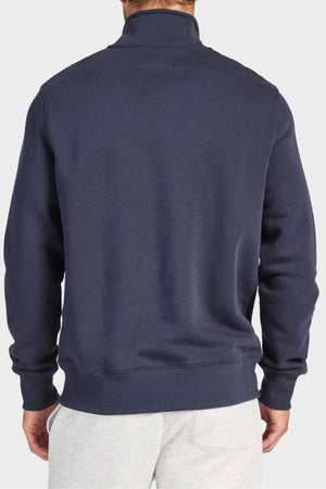 A man is shown from the back wearing the Academy Brand 1/4 Zip Sweat in premium brushed fleece with light gray pants, standing against a plain light background.