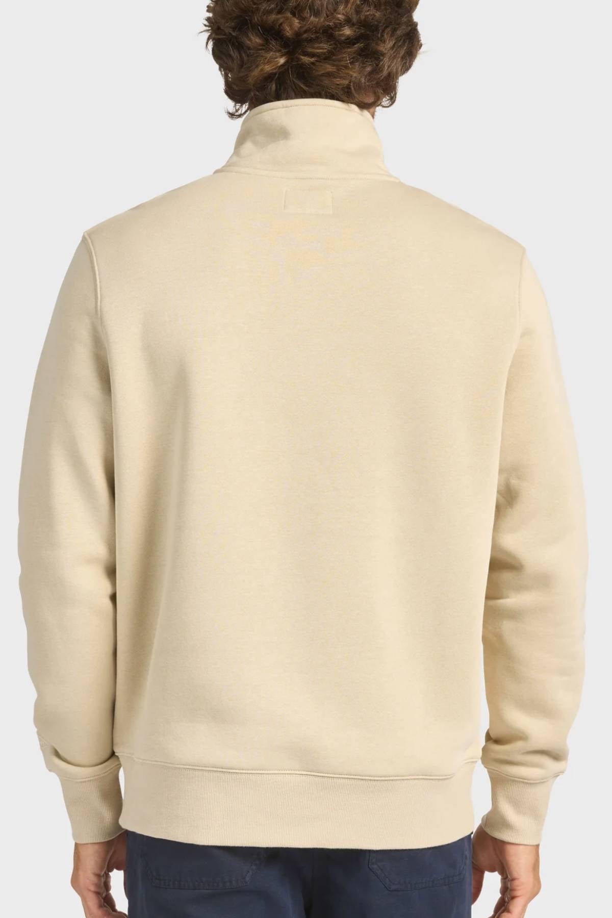 A person is seen from behind wearing the Academy Brand 1/4 Zip Sweat in light beige with long sleeves and a high collar, paired with dark pants, set against a plain light background.