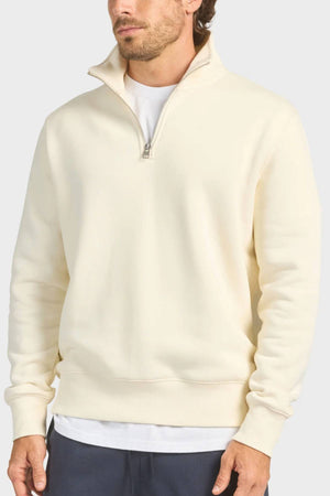 A man wearing the Academy Brand 1/4 Zip Sweat in cream over a white T-shirt and dark pants, shown from the thighs up against a plain light background.
