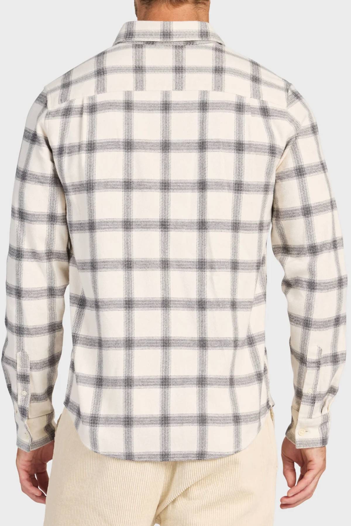 A person wearing the Academy Brand Buhler Shirt in cream with a gray plaid yarn dye twill, long sleeves, workwear buttons, untucked and viewed from the back, paired with light beige pants.