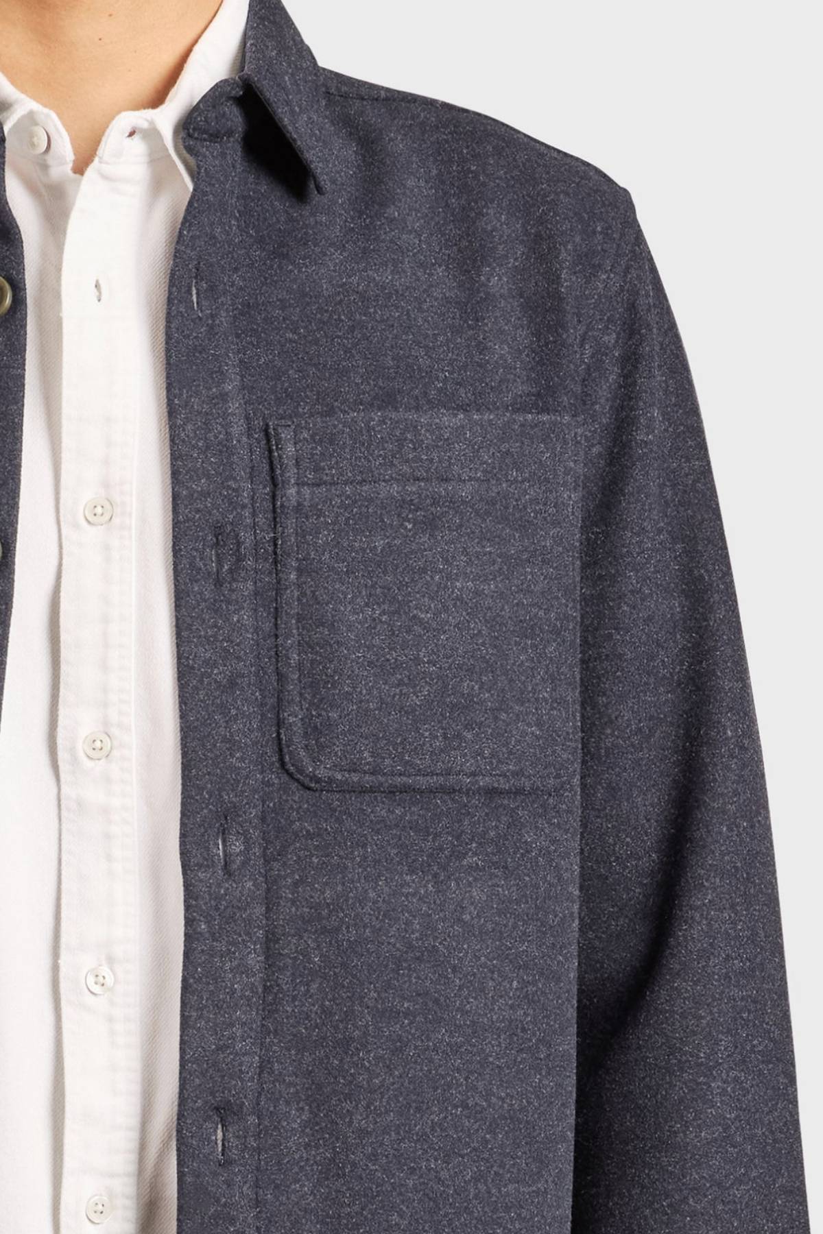 Someone shown from shoulders to waist wears the Academy Brand Lloyd Overshirt in dark gray over a white button-up, featuring a chest pocket.