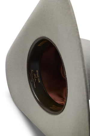 A close-up of the inside of a light gray Akubra Outback Club hat, featuring a brown satin lining and a black leather sweatband with gold writing and a Lee Kernaghan signature, celebrating Australian country music style.
