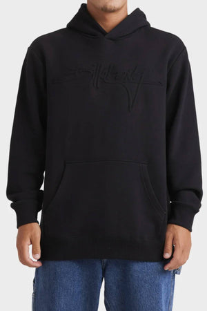 Wearing the black Billabong Tonal Boss Pop Hood— a fleece pullover with a front pocket and embossed chest text—paired with blue jeans, the person stands before a plain light background.