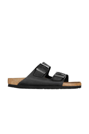 A Birkenstock Arizona sandal in black, featuring two buckle straps and a cork footbed, is shown on a white background. The sandal has a simple, minimalist design with a rubber sole.