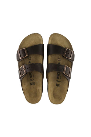 A pair of Birkenstock Arizona sandals in brown, featuring two adjustable buckle straps on each foot, set against a white background. The beige soles have visible branding and size information printed in black on the footbeds.