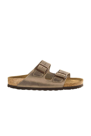 A Birkenstock Arizona sandal in brown boasts two adjustable straps with metal buckles. The cork footbed provides comfort, while the black, textured sole ensures grip. The sandal is displayed with a side profile view.