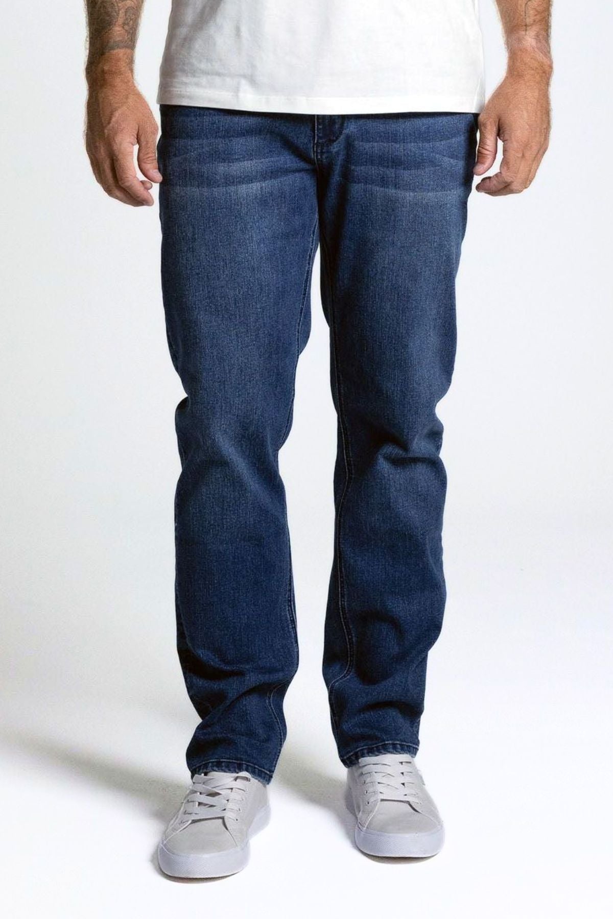 Wearing BLKWD Basing Denim Jean Straight Fit and light gray sneakers, a person stands facing forward against a plain white background. Only the lower half of their body is shown.