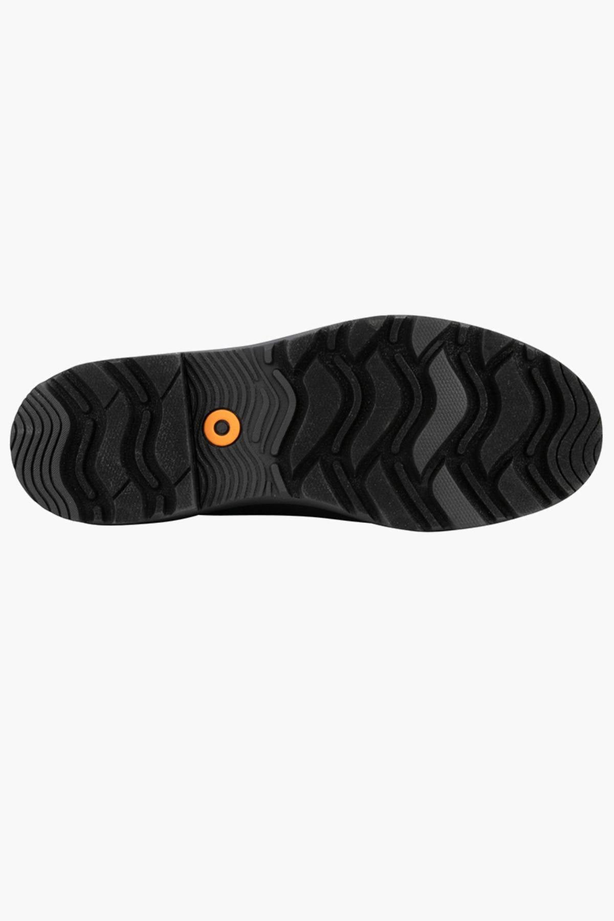 The image shows the black rubber sole of BOGS Holly Chelsea Waterproof Boots, featuring a wavy tread pattern and an orange circular detail near the heel, suggesting rebound cushioning, all displayed on a plain white background.
