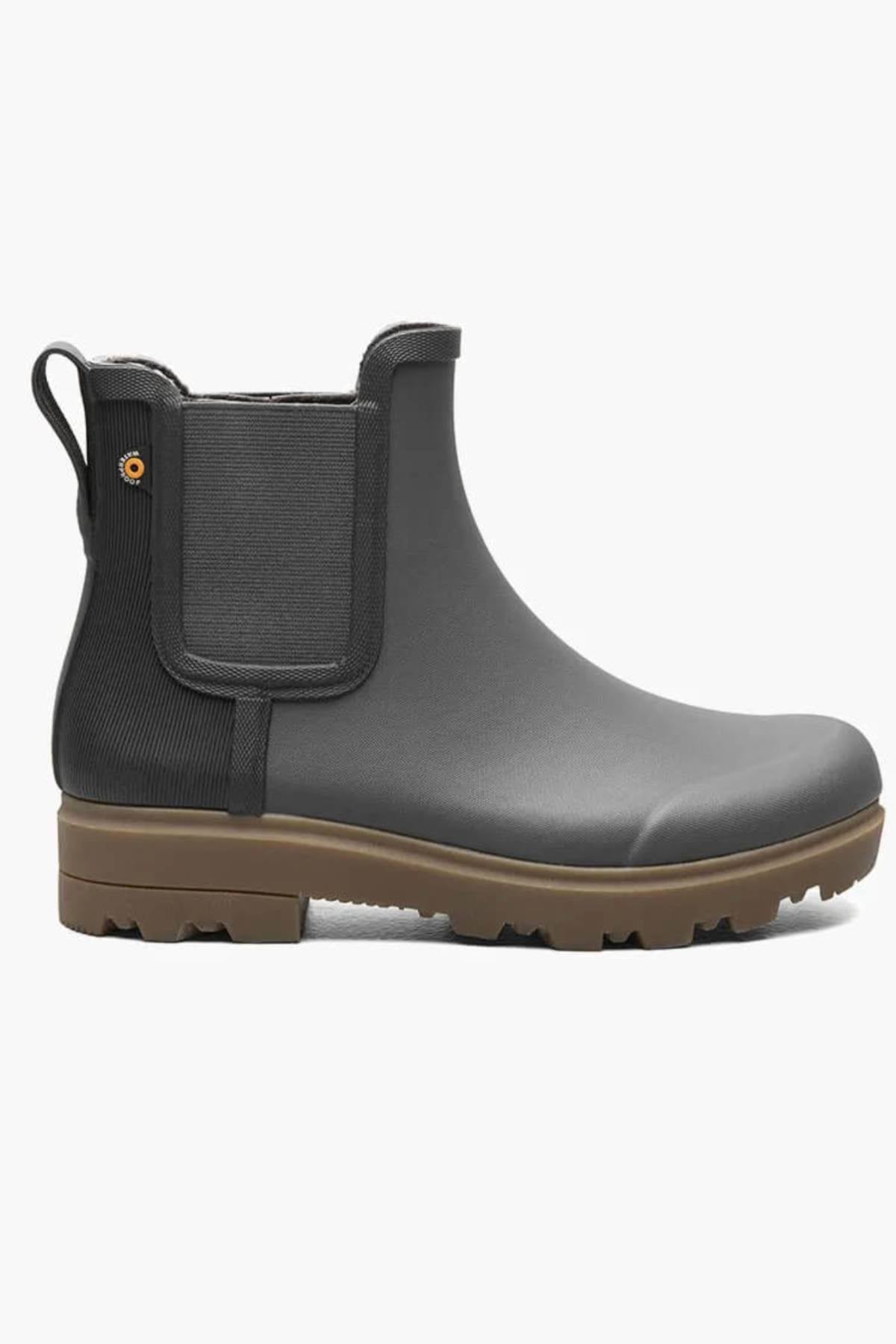 A single BOGS Holly Chelsea Waterproof Boot in gray, featuring black elastic side panels, a back pull tab, a brown rubber sole with BLOOM Algae Footbeds, is shown on a white background.