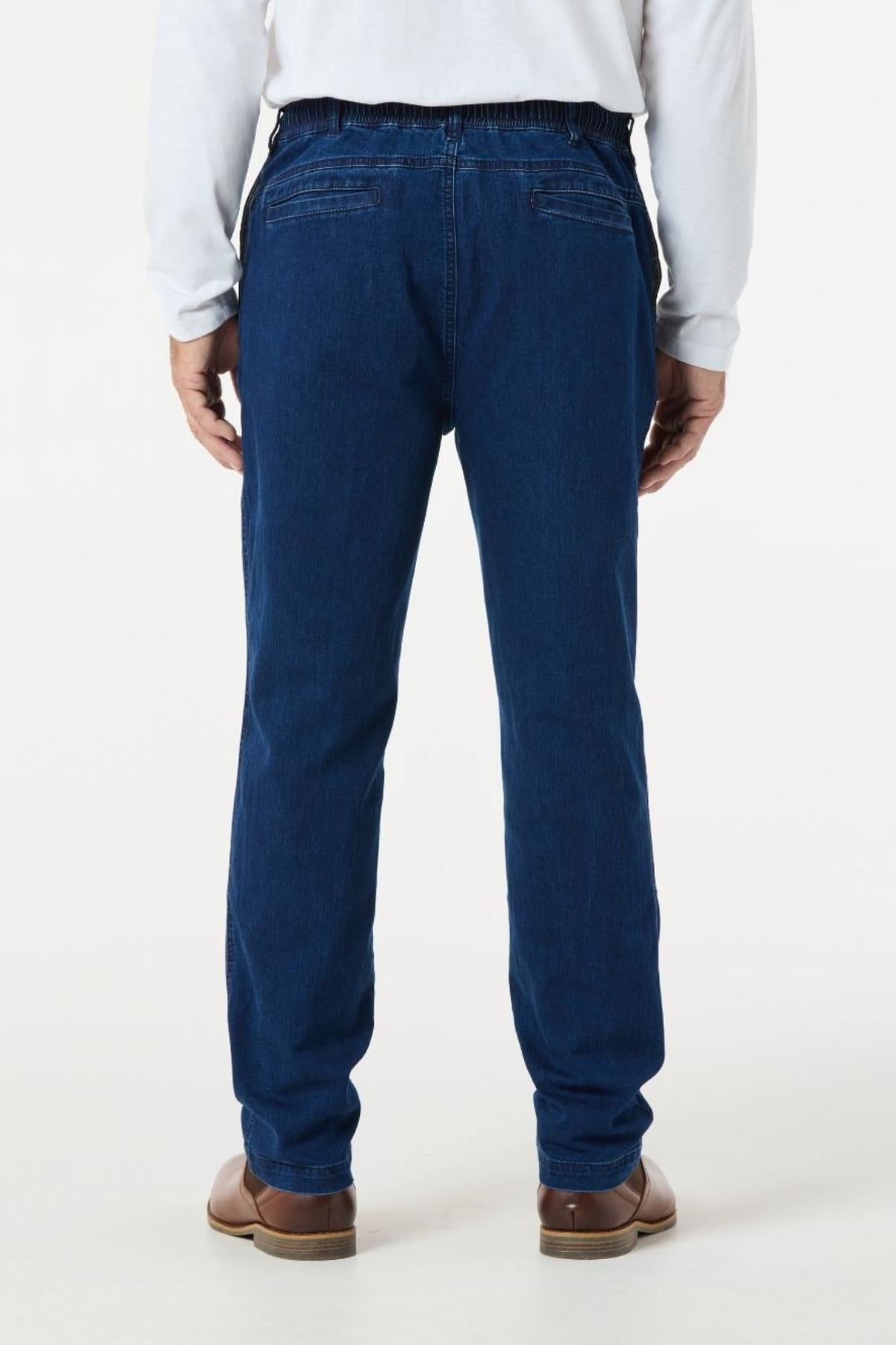 The individual is standing with their back to the camera, wearing a gray long-sleeve shirt, Breakaway Intense Denim Jean in dark blue featuring a straight leg design, and brown shoes.
