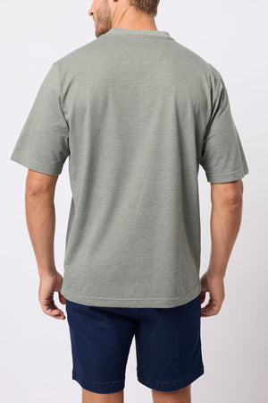 A man faces away from the camera, highlighting the relaxed fit and lightweight fabric of the light gray Breakaway Kinnersly Crew, paired with dark blue shorts against a simple light backdrop.