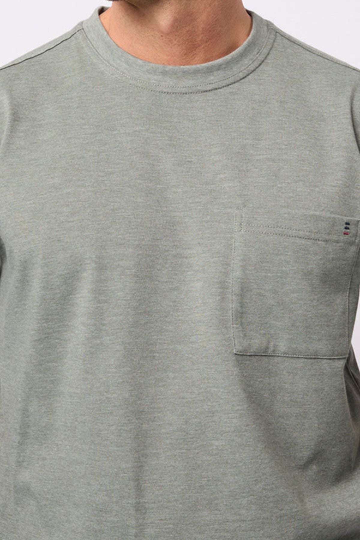 A person wears the Breakaway Kinnersly Crew, a light gray-green crew neck t-shirt featuring a left chest pocket, shown from shoulders to mid-torso. The lightweight fabric provides comfort and a relaxed fit.