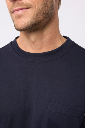 A close-up of a man in the Breakaway Kinnersly Crew, a dark navy crewneck t-shirt with a left chest pocket. The relaxed fit tee shows only his lower face, neck, and upper chest.