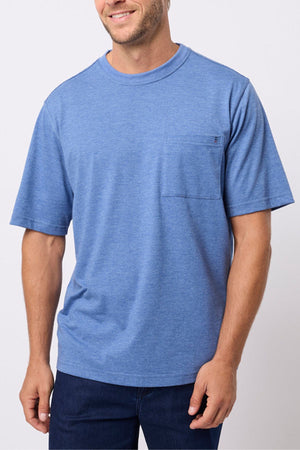 A man smiles as he models the Breakaway Kinnersly Crew, a light blue short-sleeve t-shirt with a chest pocket and relaxed fit, against a plain white background. Only his upper body is shown.