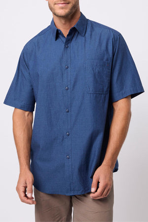 A man in the Breakaway Olivero Shirt, a short-sleeve 100% cotton button-up with a chest pocket, and beige pants stands against a plain light background.