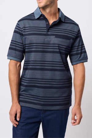 A man wearing the Breakaway Ryle Micro Prima Polo in dark blue with horizontal stripes and navy blue pants stands against a plain light background, his face partially out of frame.