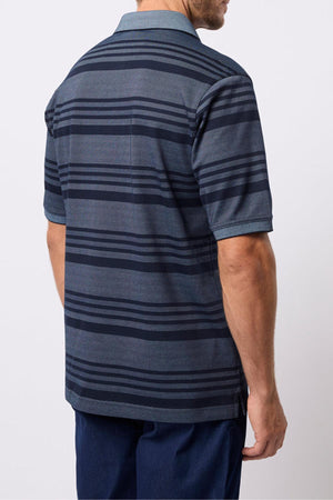 A man is seen from behind wearing the Breakaway Ryle Micro Prima Polo, a men's striped polo shirt in dark gray and navy, with dark blue pants against a plain, light backdrop.