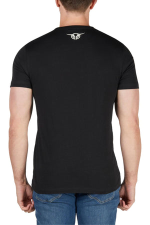A man seen from behind wears the Bullzye Dusk Tee, a soft cotton jersey with a small white logo on the upper back, paired with blue jeans for a classic style.