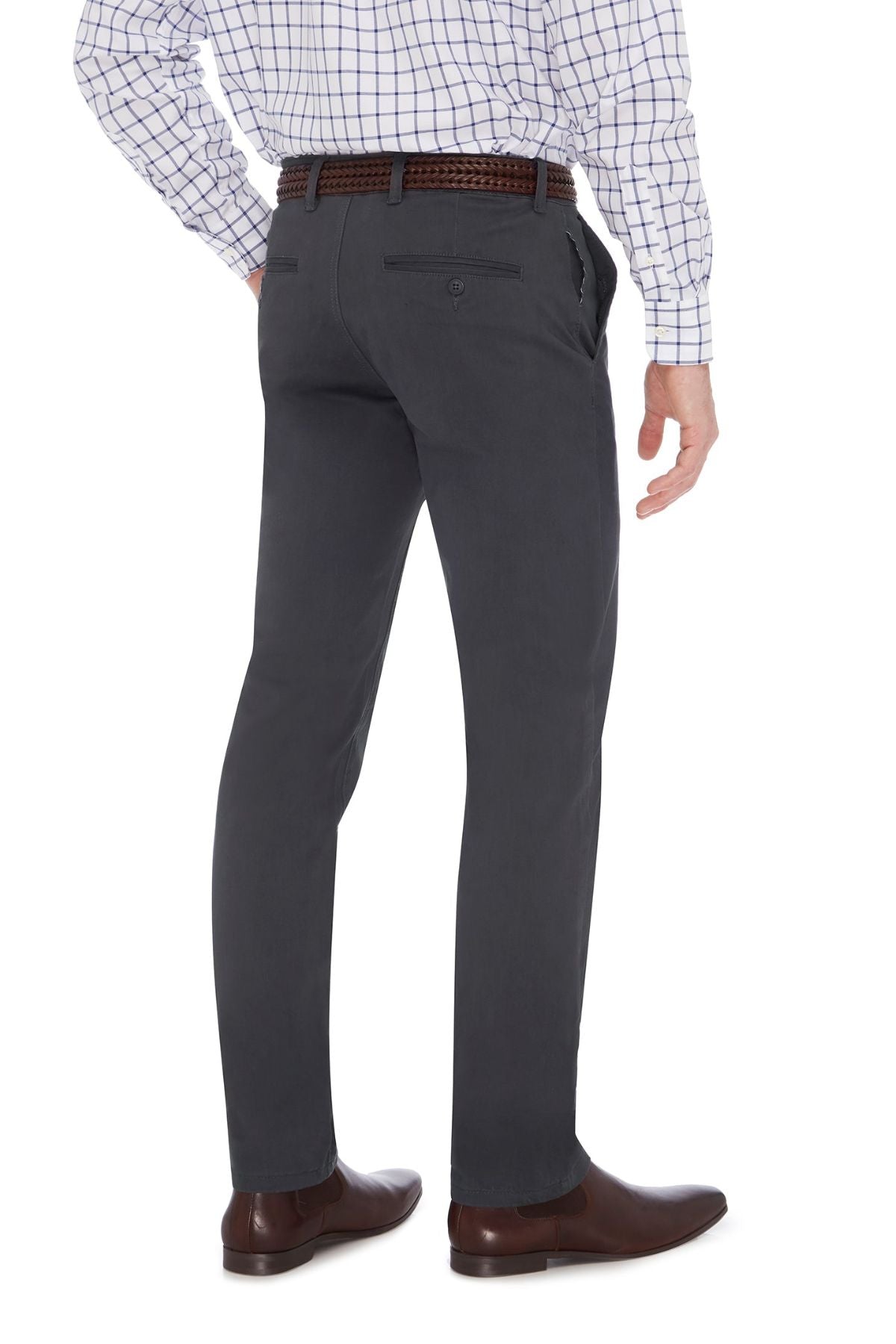 A person is shown from the waist down, standing with one hand in their pocket. They are wearing dark City Club Hammond Place Pants, a checkered shirt tucked in, a brown belt, and brown dress shoes. The pants have back pockets with buttons and feature a tapered slim fit. The background is plain white.