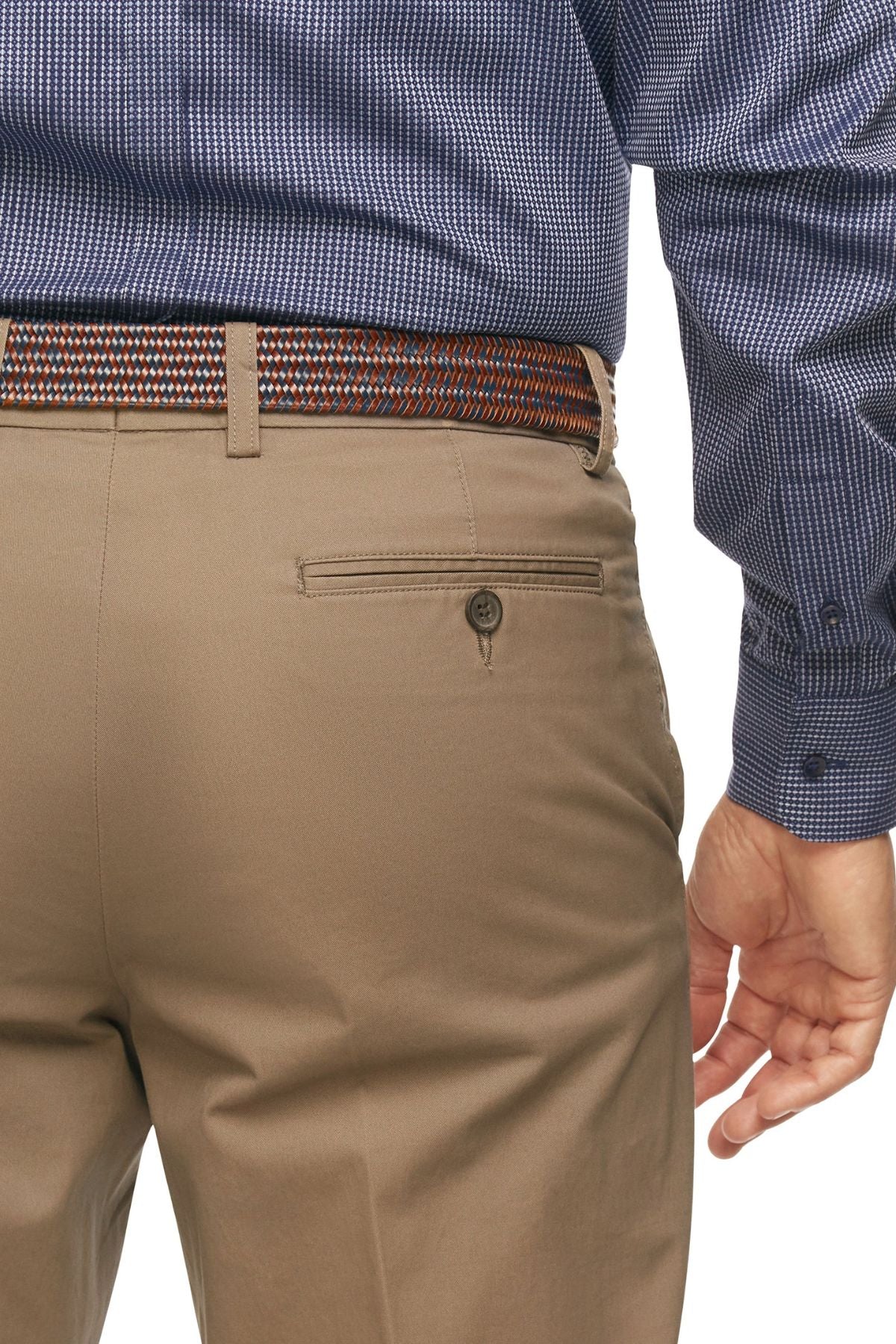 A person wearing City Club Mariner Harbour Pant made from a blend of Cotton and Spandex, featuring brown dress pants with elasticated sides, a buttoned back pocket, and a woven belt in a brown, white, and orange pattern. The person is also dressed in a long-sleeved, dark blue patterned dress shirt. The image focuses on the lower back and waist area of the attire.