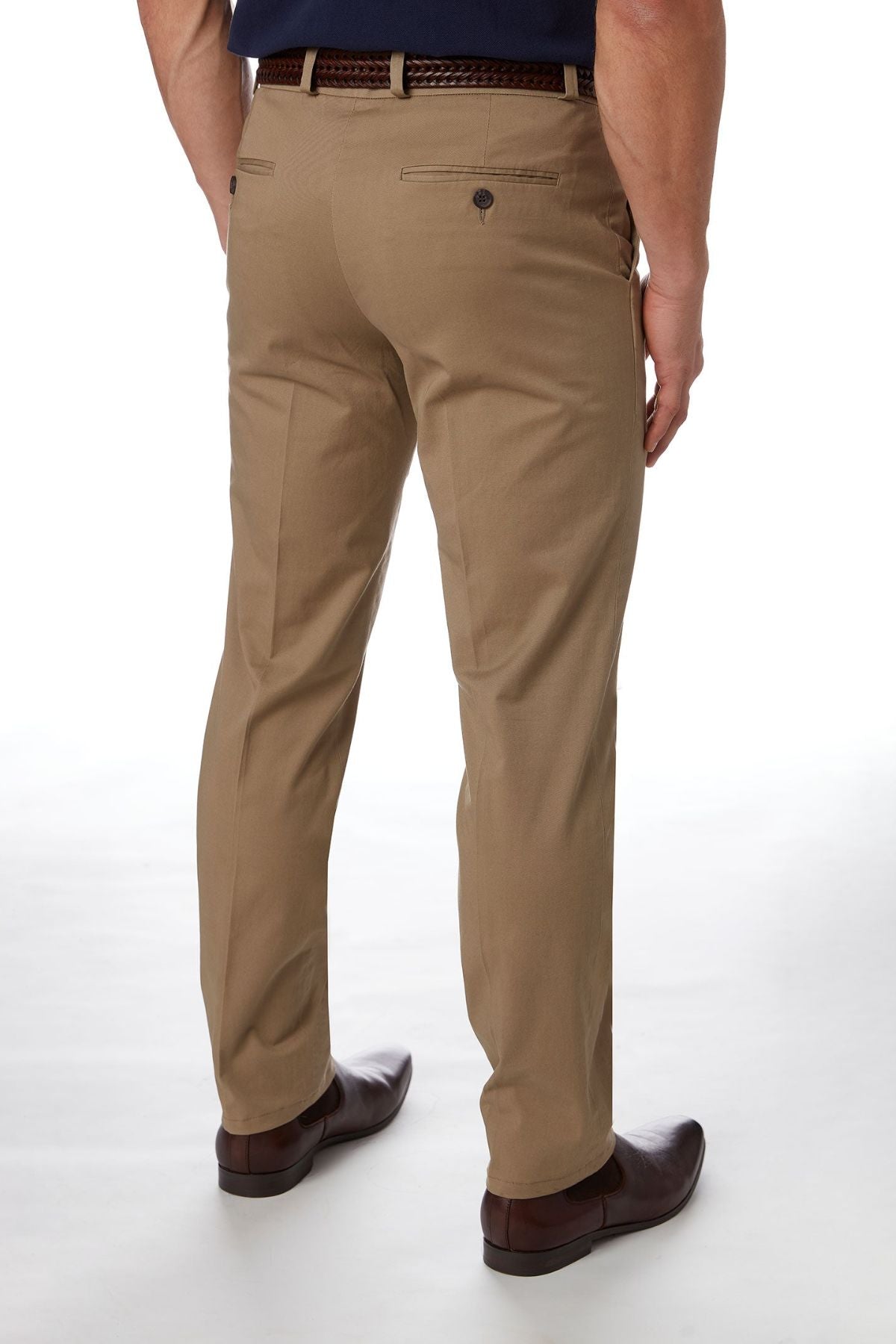 A man is seen from the back wearing City Club Navigator 1770 Pants in a slim fit khaki color, accompanied by a black belt and dark brown dress shoes. The comfortable pants feature back pockets with buttons, and the man is standing against a plain white background.