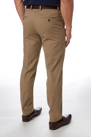 A man is seen from the back wearing City Club Navigator 1770 Pants in a slim fit khaki color, accompanied by a black belt and dark brown dress shoes. The comfortable pants feature back pockets with buttons, and the man is standing against a plain white background.