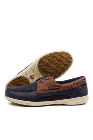 The Colorado Askit Casual Shoe is a navy blue and brown leather boat shoe with white slip-resistant soles. One stands upright, showing its herringbone tread. It features metal eyelets and leather lacing on the sides for added style.