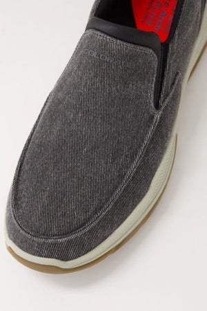 Close-up of the Colorado Kanza Canvas Shoe: gray slip-on with textured fabric upper, white midsole, brown slip-resistant outsole, visible elastic panel, and red insole with printed text.