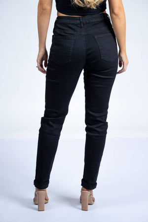 A woman faces away from the camera wearing Country Denim Relaxed Mum Jean in black, paired with a black crop top and nude heeled sandals, set against a plain white background.