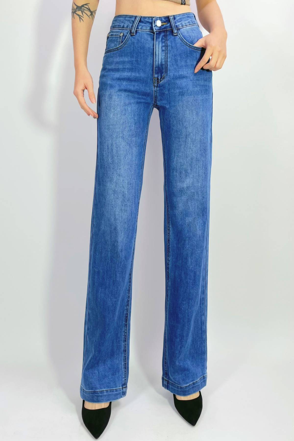 Someone stands against a plain light background, wearing the Country Denim Straight Leg Stretchy Jean and black pointed-toe heels. Only their lower body is visible; the upper torso and face are not shown.