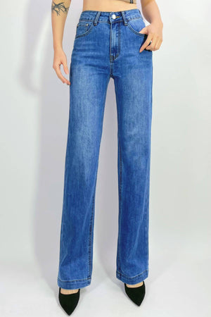 Someone stands against a plain light background, wearing the Country Denim Straight Leg Stretchy Jean and black pointed-toe heels. Only their lower body is visible; the upper torso and face are not shown.