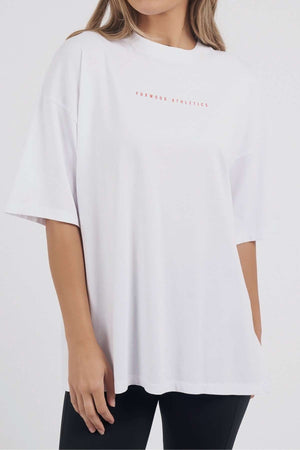 A woman models the Foxwood Captain Tee, a loose-fitting, oversized white cotton T-shirt with short sleeves, paired with black pants against a light background—ideal for casual occasions.