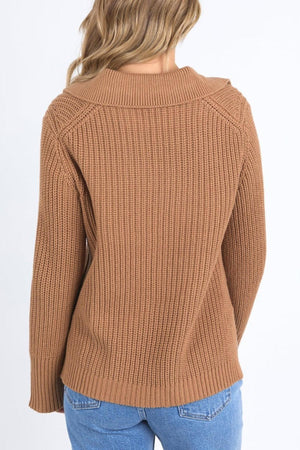 A person with wavy, light brown hair wears the relaxed fit Foxwood Carlton Knit in brown with blue jeans, photographed from the back against a plain white background for an effortless, comfortable look.