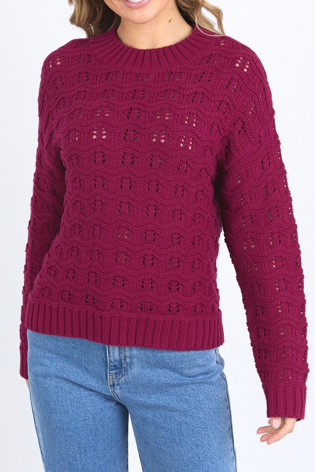 A woman wears the Foxwood Carter Knit, a textured dark pink sweater with a round neck and long sleeves, styled with light blue jeans against a white background.