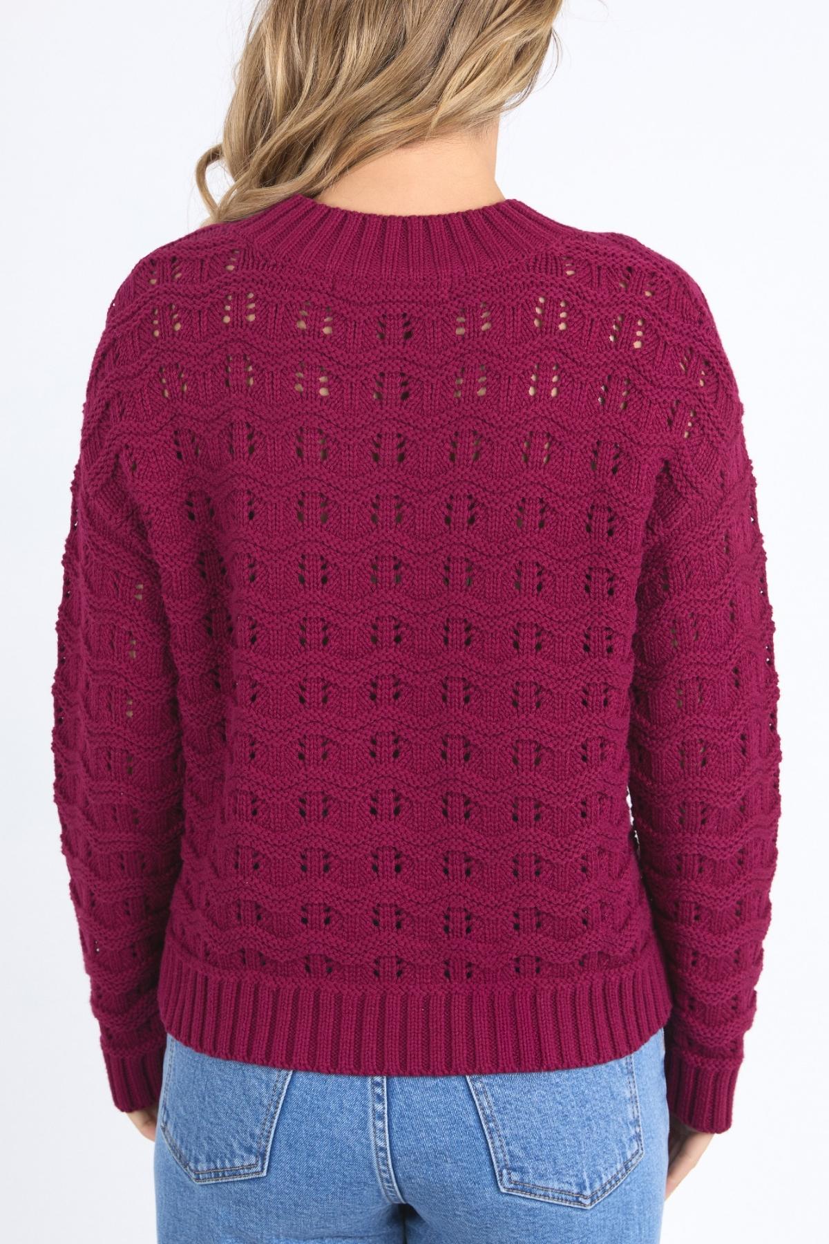 Seen from behind, a person with wavy blonde hair wears a dark red Foxwood Carter Knit sweater and light blue jeans, standing against a plain white background.