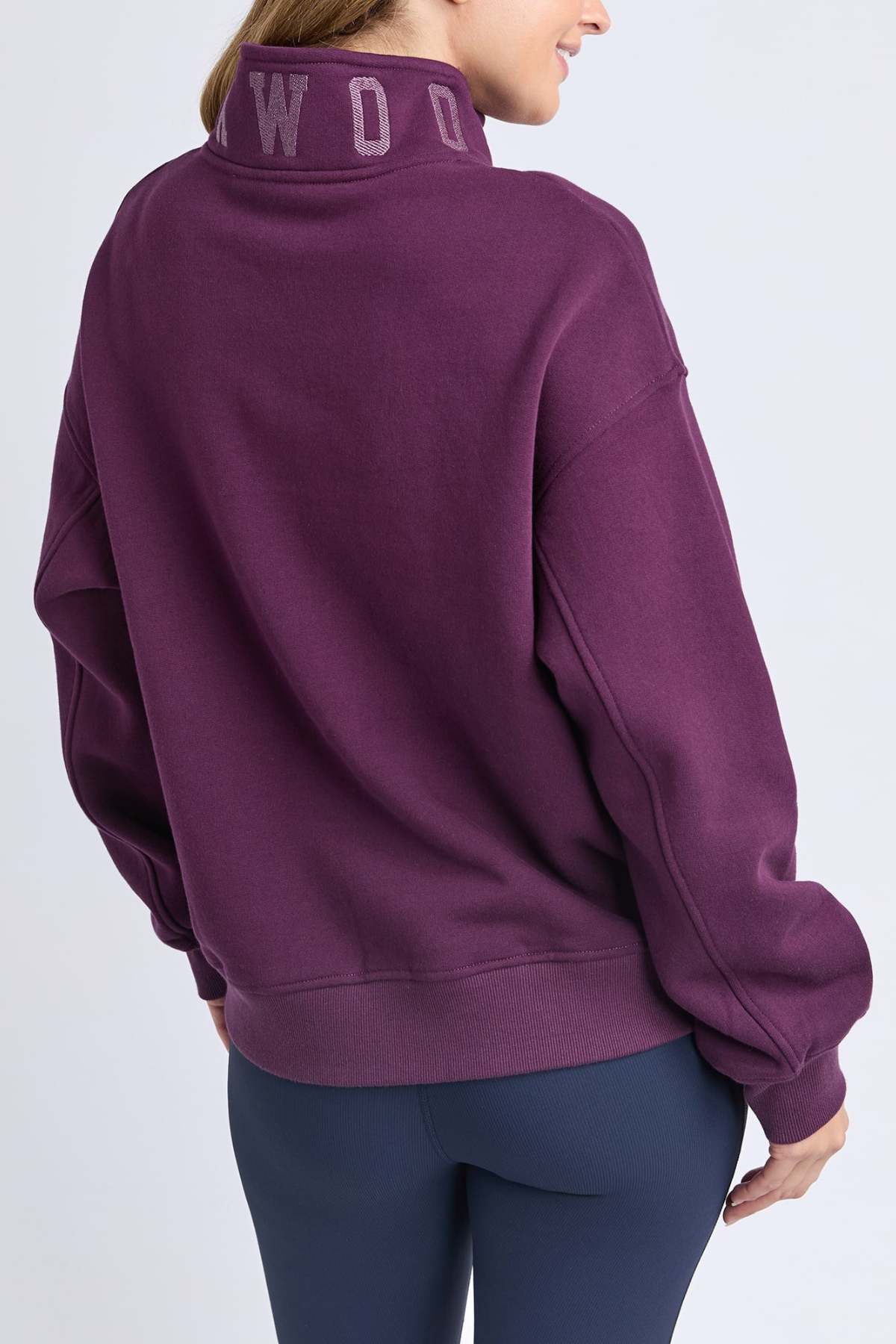 A person is seen from the back wearing the loose-fitting, 100% soft cotton Foxwood College Zip Crew in purple with an embroidered collar and dark leggings, against a light background.