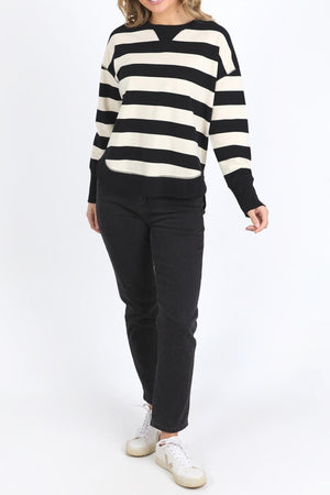 A person wearing a Foxwood Delilah Stripe Crew, black pants, and white sneakers stands against a plain white background.
