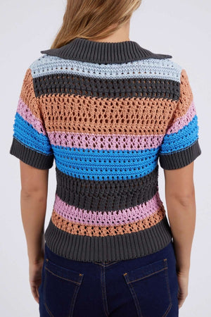 A person in a short-sleeve Foxwood Gazelle Stripe Knit sweater with gray, brown, pink, blue, and light blue stripes stands facing away wearing dark jeans. This cotton top features a textured pattern and versatile colors.