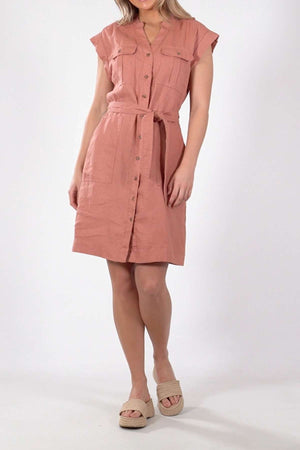 A model displays the knee-length Foxwood Harlow Dress in light pink, featuring short sleeves and a belted waist for a flattering silhouette. The linen dress is paired with beige platform sandals, all set against a plain white background, emphasizing its elegance.