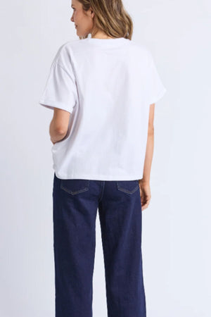 A person faces away, wearing a Foxwood Huntleigh Oversized Tee and dark blue jeans, standing against a light background.