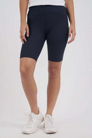 A person stands against a plain white background, wearing the Foxwood Luxe Rib Short in black, featuring an elastic waist, paired with a white top and white sneakers. The image is cropped from the waist down.