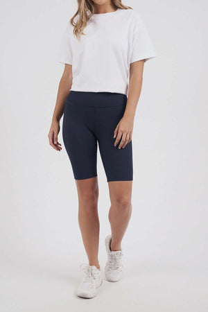 A person stands against a plain light background wearing a white t-shirt, white sneakers, and Foxwood Luxe Rib Short with an elastic waist. Their face is not visible.