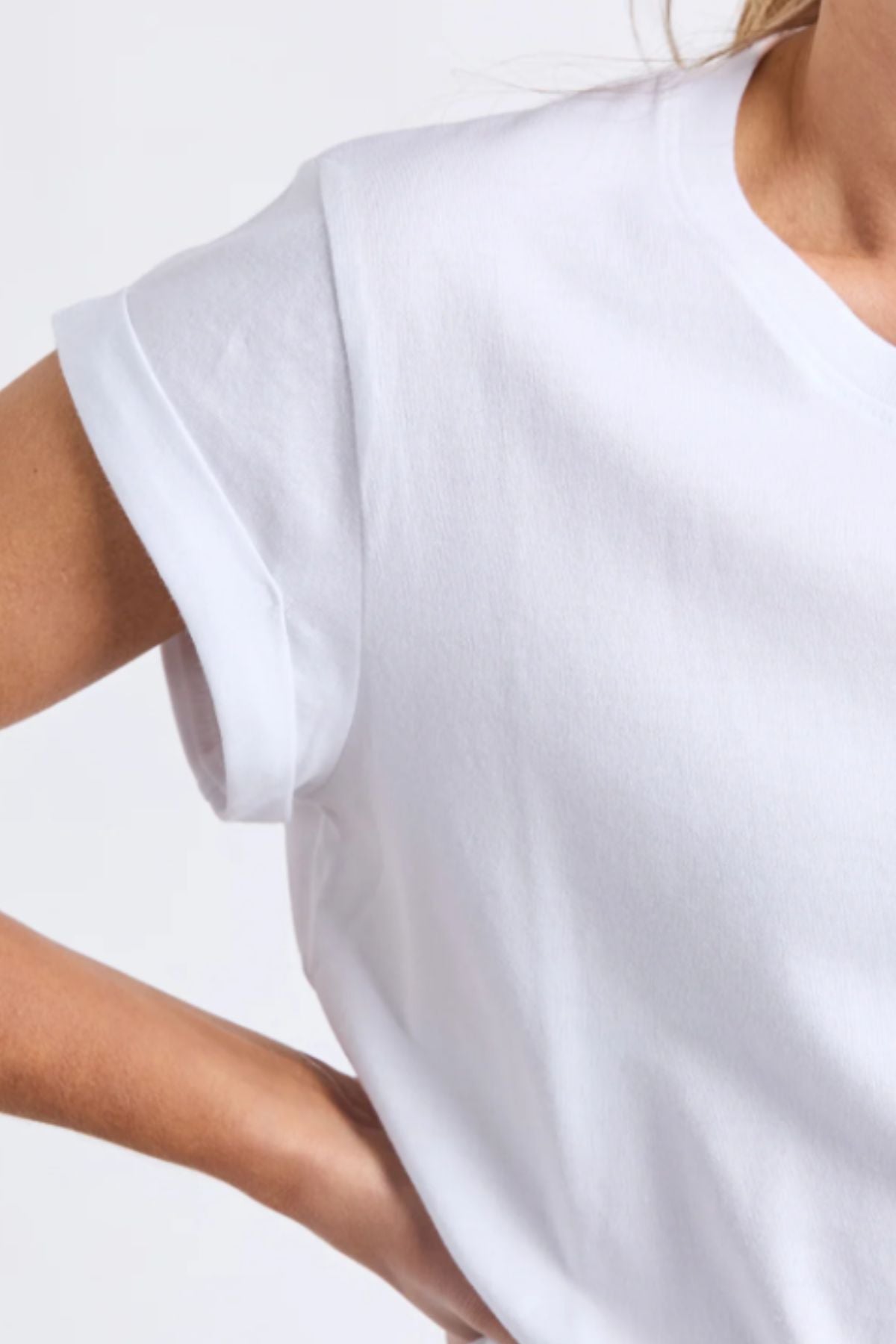 Wearing the Foxwood Manly Tee—women’s cotton t-shirt with rolled sleeves—this person is shown from shoulders to upper torso, arm bent and hand on hip against a plain light background for an effortlessly casual look.