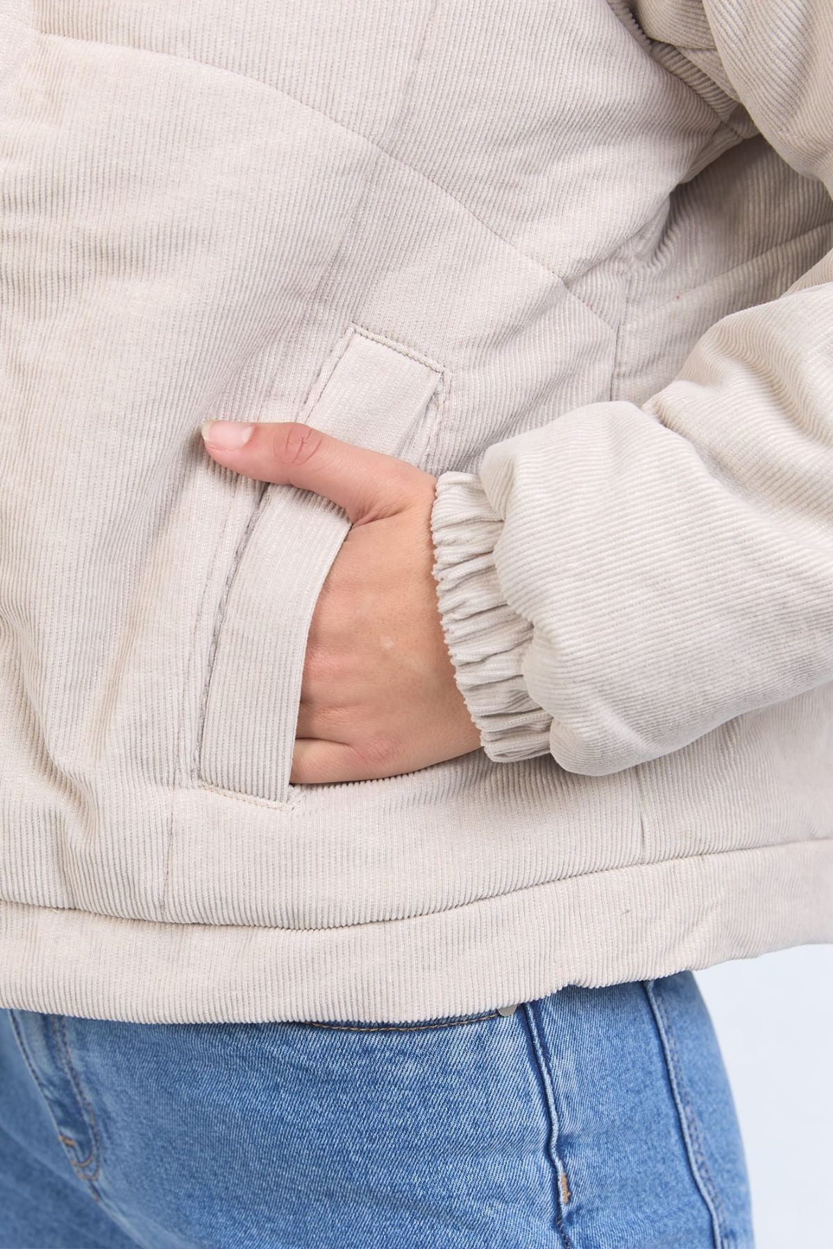 A close-up of a person wearing the Foxwood Rosalee Cord Jacket in light beige, made from 100% cotton corduroy, with their hand in the side pocket. They are also wearing blue jeans.