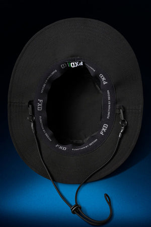 The FXD CP-14 Boonie Hat, shown from above in black, is made for outdoor work with an adjustable chin strap and inner band printed "FXD FUNCTION BY DESIGN" in white. A gradient blue background highlights its sun protection style.