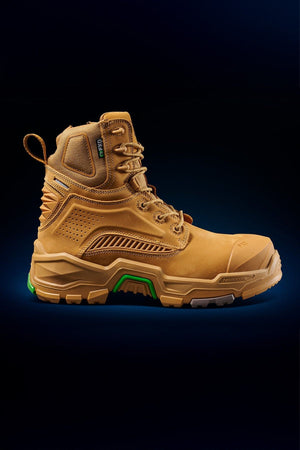 The FXD Dura X-1 Nitrocore™ High Cut Work Boot is tan with detailed stitching, rugged soles, and green accents, shown in profile against a dark blue gradient background.