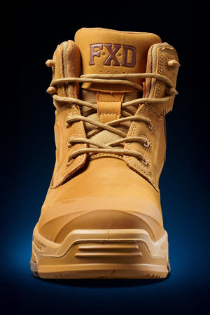 The FXD Dura X-2 Nitrocore™ Mid Cut Work Boot in tan is shown from the front, featuring visible laces, a reinforced toe, and the FXD logo on the padded tongue, set against a dark background with a blue gradient at the base.